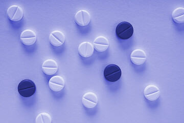 Purple background on the theme of medicine, health care, drugs, pharmacology. Light and dark pills...