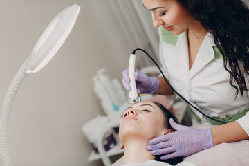 Fototapeta premium Close up of head woman receiving electroporation phonophoresis facial therapy at beauty spa salon.
