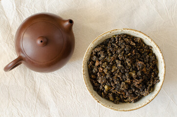 Taiwanese oolong in clay cup and clay teapot on linen background