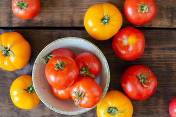 tomatoes in bowl on wooden background. Top view.