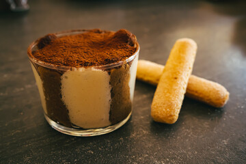 Tiramisu dans un bol en verre avec deux gateaux sur le coter