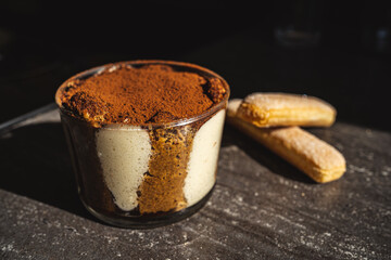 Tiramisu cake in a glass bowl with two angel finger bscuits