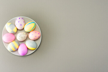Colorful easter eggs on plate on gray background
