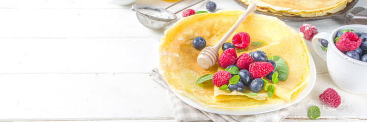 Eastern European traditional Maslenitsa holiday. Cooking crepe pancakes, with ingredients, honey and fresh berries
