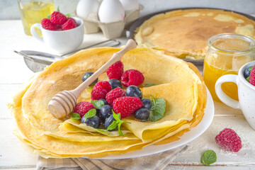 Eastern European traditional Maslenitsa holiday. Cooking crepe pancakes, with ingredients, honey and fresh berries