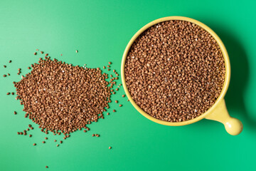 Top view of buckwheat t in the bowl over green background, with copy space.