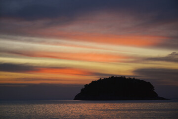 Naklejka na ściany i meble Silhouette of an island against a sunset sky
