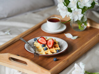 breakfast in bed. romantic breakfast. Viennese waffles with strawberries. composition of waffles with strawberries and flowers. high key