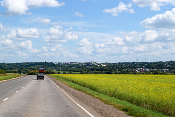 Fototapeta na wymiar asphalt road in the countryside surroiunded by rapeseed fields in Russia