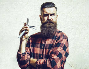 Young hipster hairdresser. Bearded man in barber shop. Barber scissors and straight razor, barber shop. Portrait bearded man. Mustache men. Brutal guy, scissors, straight razor.