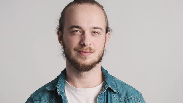 Positive bearded guy opening eyes after meditation and smiling on camera isolated on white background