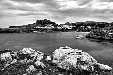 a bay with a rocky coast, the town of Lindos and a medieval fortress