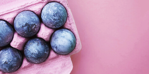 bright modern banner for the holiday easter blue gray marble painted eggs in a pink box for eggs on a pink background, place for text, top view 