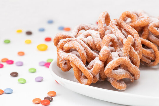 Traditional Finnish May Day funnel cake (tippaleipa) on the white plate with colorful small candies. Close up.