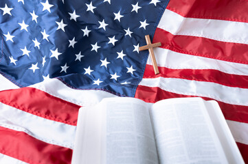 Open Holy bible and Wooden cross over American flag background. 