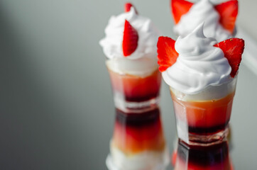 Colorful layered shots of drinks based on vodka, grenadine and orange juice decorated with whipped cream and pieces of strawberry in the shape of bunny ears