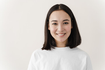 Portrait of a beautiful, happy girl. Young woman standing on a white wall background sincerely smiling. Place for text, copy space.