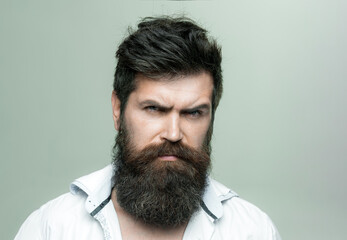 Man with long beard, mustache and stylish hair, light background. Macho on strict face, wears unbuttoned shirt. Guy with modern hairstyle visited hairdresser. Barbershop or hairdresser concept.