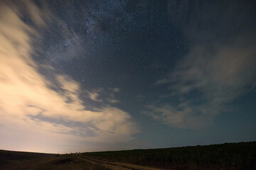 Cloudy night sky with stars and milky way and meteor shower. Night landscape.