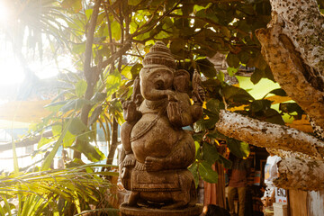 Posąg statua hinduskiego Boga Ganesha, na jasnym roślinnym tle. - obrazy, fototapety, plakaty