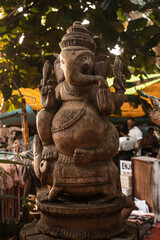 Posąg statua hinduskiego Boga Ganesha, na jasnym roślinnym tle. - obrazy, fototapety, plakaty