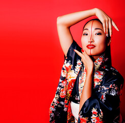 young pretty geisha on red background posing in kimono, oriental