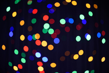 Christmas or New Year dark background. Festive glowing background. Defocused background with colorful blinking garland. Blurred bokeh.