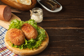 Scotch eggs on lettuce leaves on a dark wooden table with cooking ingredients. Close-up, horizontal, copy space