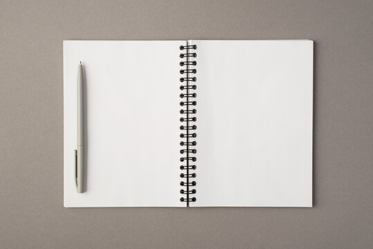 Above photo of empty notebook and grey pen isolated on the grey background