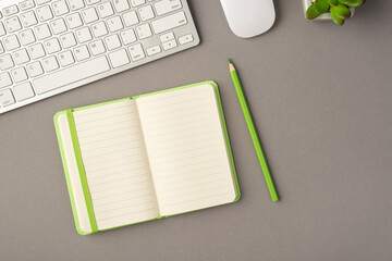 Above photo of plant keyboard computer mouse green notebook and pencil isolated on the grey background with blank space