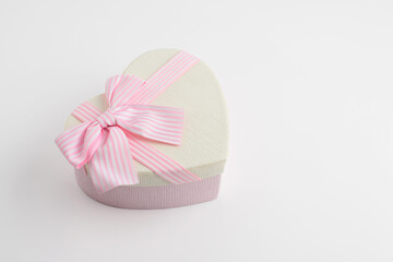 Fototapeta na wymiar Beautiful pink heart-shaped gift box with a ribbon and a beautifully tied pink bow. Gift wrapping for a gift or surprise for a loved one.