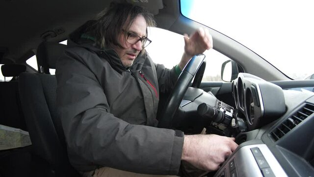 Man turning the car key to start the vehicle but it doesn't work so he gets frustrated and tries again many times