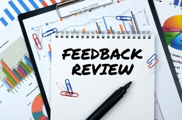 On the table are reports, charts, a notebook with the inscription - FEEDBACK REVIEW