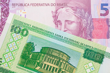 A macro image of a pink and purple five real bank note from Brazil paired up with a green one hundred ruble note from Belarus.  Shot close up in macro.