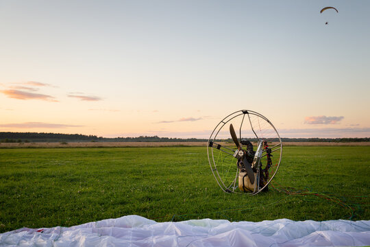 Individual parajet backpack with a no-spin engine and spread wing on the takeoff field. Wing flight preparation. Extreme sports. Paragliding and small aircraft.