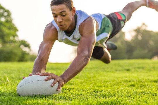 Athletic athlete in action jumping in the air for the rugby ball on the grass. Sport.