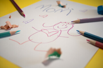 child drawing for mom with color pencils on yellow background