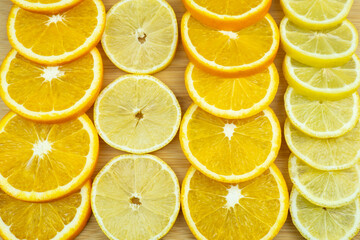 Slices of lemons and oranges on a wooden board. Close-up pattern of fruits