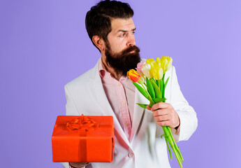 Businessman with gift and bouquet. Romantic man with tulips and present. Valentines Day, Womens Day, birthday.