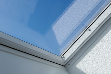 Close up view at white window Skylights with raindrop on glass at attic and background of sunny blue sky.