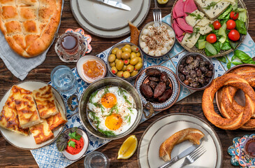 Delicious rich Traditional Turkish breakfast include tomatoes, cucumbers, cheese, butter, eggs, honey, bread, bagels, olives and tea cups. Ramadan Suhoor aka Sahur (morning meal before fasting). 