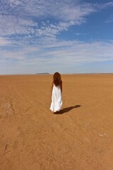 Woman in white dress in Sahara desert 