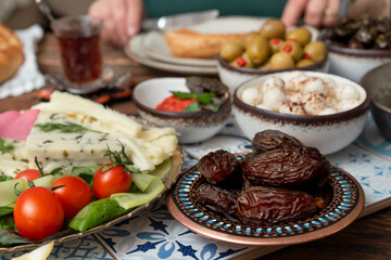 Delicious rich Traditional Turkish breakfast include tomatoes, cucumbers, cheese, butter, eggs, honey, bread, bagels, olives and tea cups. Ramadan Suhoor aka Sahur (morning meal before fasting). 