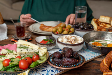 Delicious rich Traditional Turkish breakfast include tomatoes, cucumbers, cheese, butter, eggs, honey, bread, bagels, olives and tea cups. Ramadan Suhoor aka Sahur (morning meal before fasting). 