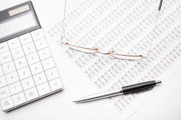 Calculator pen and glasses on the white background. Finance concept