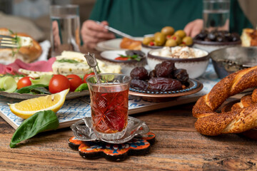 Delicious rich Traditional Turkish breakfast include tomatoes, cucumbers, cheese, butter, eggs, honey, bread, bagels, olives and tea cups. Ramadan Suhoor aka Sahur (morning meal before fasting). 