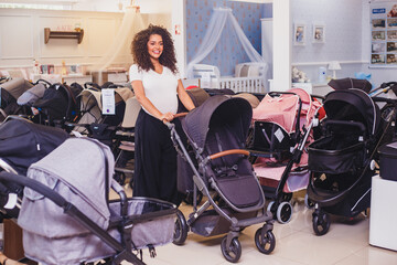 Afro pregnant woman choosing which stroller she wants to buy, in a maternity goods store for...