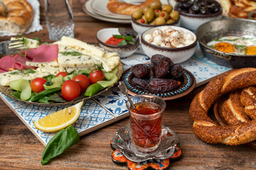 Fototapeta na wymiar Delicious rich Traditional Turkish breakfast include tomatoes, cucumbers, cheese, butter, eggs, honey, bread, bagels, olives and tea cups. Ramadan Suhoor aka Sahur (morning meal before fasting). 