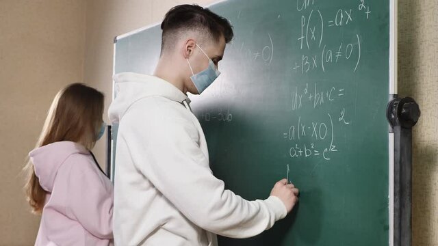 Group of students with face mask writing on the board in the classroom during pandemic