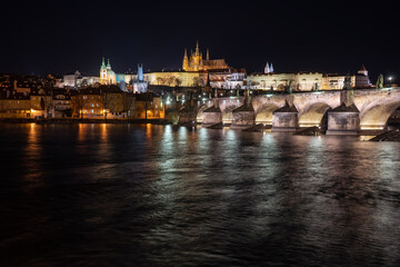 .view of the illuminated Prague Castle and the Cathedral of St. Vitus and Charles Bridge on the Vltava River at night in the center of Prague in the Czech Republic